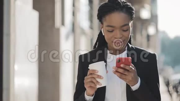 穿西装的年轻非裔美国女商人使用智能手机语音识别功能在线饮酒视频的预览图