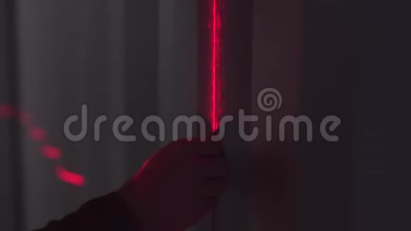 男人剪影拿着厚厚的线在墙上与条形码扫描仪的红线在黑暗中库存录像关闭视频的预览图