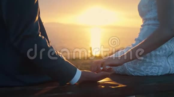 新婚夫妇手牵手在金色的夕阳背景下摇摆视频的预览图