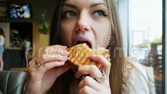 一位饥饿的年轻女士在咖啡馆快餐店吃烤面包视频的预览图