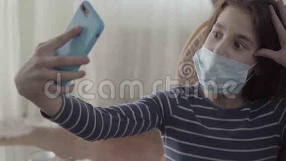 肖像快乐可爱的十几岁女孩自拍她的蓝色手机坐在扶手椅在家关门A视频的预览图