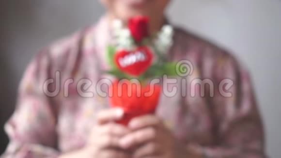 带着微笑的亚洲女士给你一盆红色玫瑰为了爱一个慢点视频的预览图