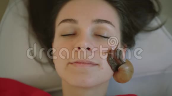 一位年轻的女士在水疗中心放松用蜗牛做面部按摩蜗牛吃的是死皮视频的预览图