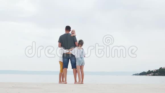 年轻夫妇和他们的三个孩子在白沙滩上家庭旅行快乐的家庭度假视频的预览图