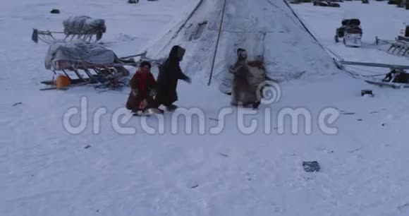 三个来自西伯利亚蒙古包营的小孩在雪天的雪橇旁玩得很开心视频的预览图