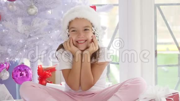 小公主坐在神奇的圣诞树旁手里拿着装饰的雪花好像它们是耳机耳环和视频的预览图