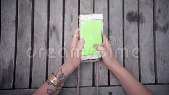 一位年轻女士的特写手她用绿色屏幕色键垂直地握住和使用电话视频的预览图