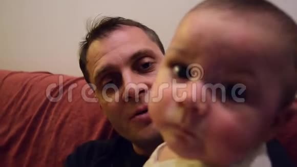 父亲正试图教他六个月大的小男孩说妈妈婴儿正把手放在嘴上用订书机视频的预览图