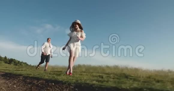 夏天在山顶徒步旅行的一对快乐的年轻夫妇在山里的爱男人和女人沿着通往视频的预览图