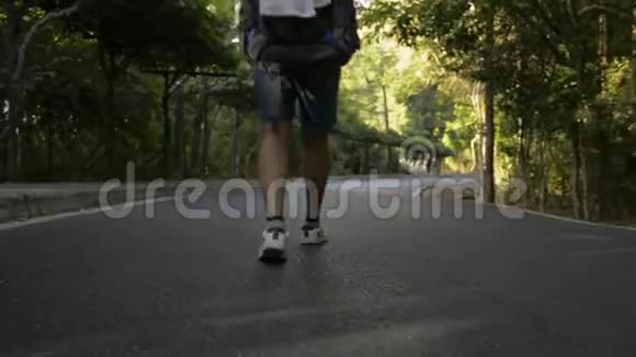后背低角度观看亚洲女性徒步旅行者与背包走过热带雨林视频的预览图