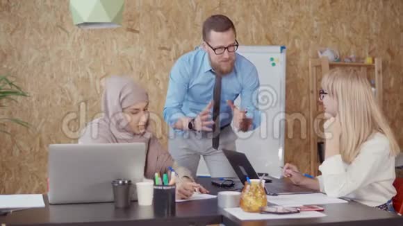 男人金发女人和穆斯林女人在工作日的办公区域讨论视频的预览图