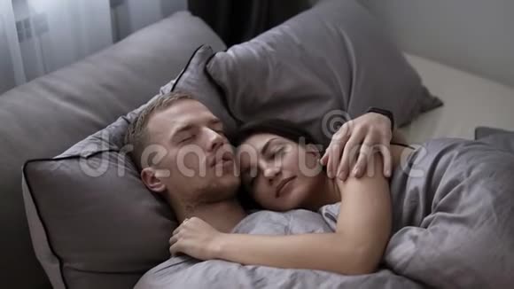美丽的一对夫妇在家里的床上在一起时微笑着拥抱着男人亲吻他的女朋友或者视频的预览图
