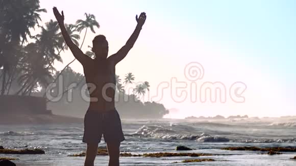早上肌肉男的侧影在海洋海岸冥想视频的预览图