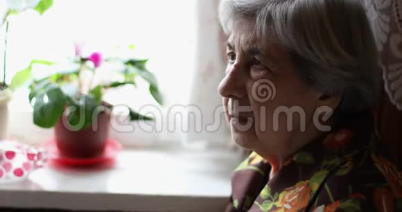 一位皱纹很深的老妇人坐在窗户附近视频的预览图
