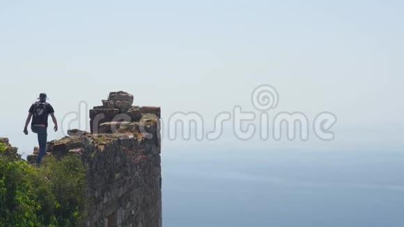 男子游客漫步在古堡墙上拍摄背景为平静的地中海视频的预览图
