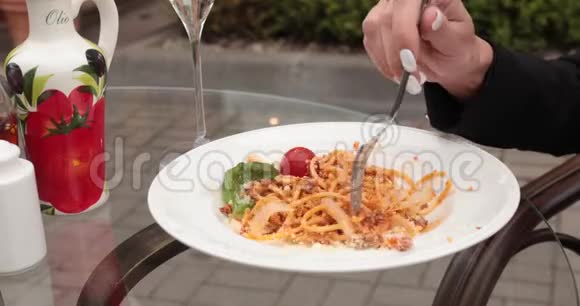 女人吃意大利面她正把意大利面放在她坐在玻璃桌上的叉子上视频的预览图