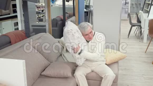 在家具店出售的柔软软垫上一位性格开朗的老人视频的预览图