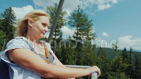 一个活跃的女人坐着缆车在被群山包围的森林里兜风视频的预览图
