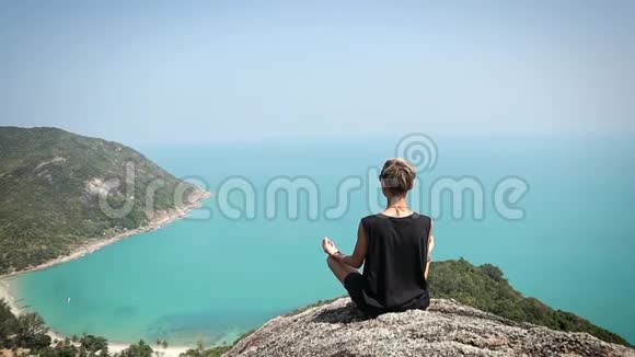 短发的年轻女子正坐在悬崖边上看风景视频的预览图