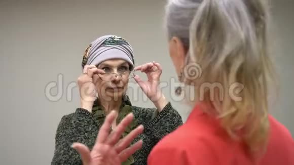 与朋友交谈时头发被绑的老年妇女摘下眼镜两个快乐成熟的女人在说话微笑视频的预览图