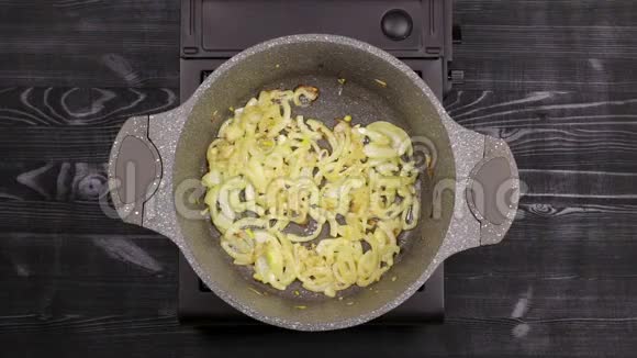切片洋葱片在平底锅中烤用大理石或石头不粘涂层涂成金黄色石油在b上沸腾视频的预览图