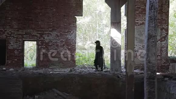一个穿着雨衣和帽子的大胡子男人穿过一个废弃的工厂走下台阶走到下面视频的预览图