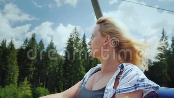 一个年轻的女人坐电梯看着周围美丽的山林视频的预览图