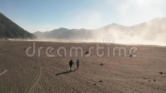 在东爪哇美丽的Bromo山附近的火山灰沙漠中行走的游客的鸟瞰图视频的预览图