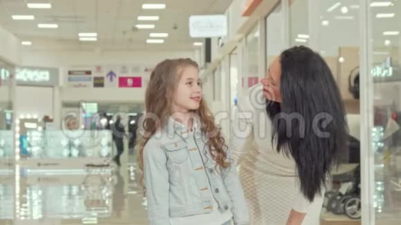 可爱的卷发小女孩和妈妈一起在商场购物视频的预览图