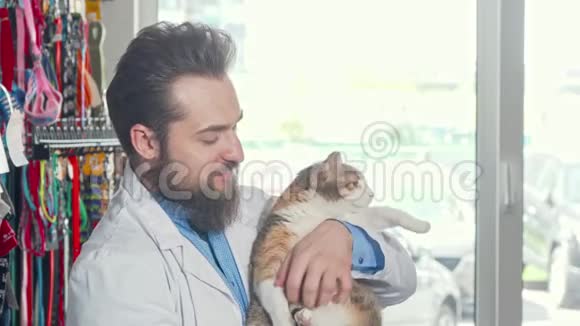 友好的兽医对着镜头微笑抱着可爱的脾气暴躁的猫视频的预览图
