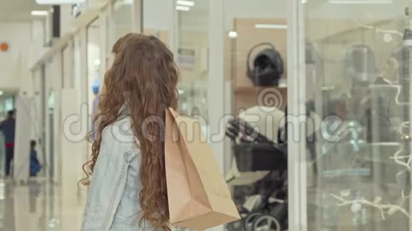 快乐的小女孩对着镜头微笑拿着购物袋在商场里视频的预览图