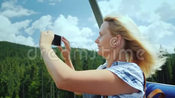 一位中年妇女拍摄美丽的风景坐在滑雪缆车的长凳上在山区度假视频的预览图
