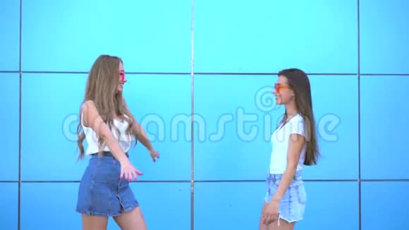 两个年轻的时髦女人在蓝墙上拥抱视频的预览图