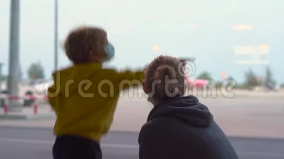 小男孩和他的母亲戴着医用口罩在机场等候他们的航班视频的预览图