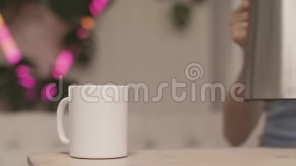 特写女人手在灯光的背景上倒茶库存录像年轻女子为自己泡了一杯茶视频的预览图