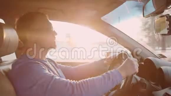 人开车唱歌日落和穿过树木的阳光在背景上视频的预览图