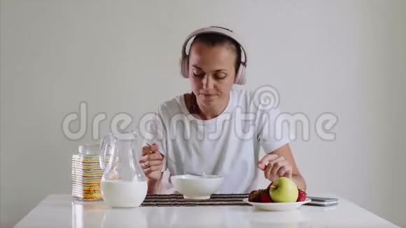戴着耳机的女人一边听音乐一边吃着牛奶的玉米片视频的预览图