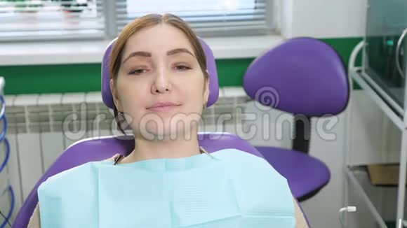 牙医在检查前给坐在牙科椅上的病人年轻妇女戴上眼镜视频的预览图