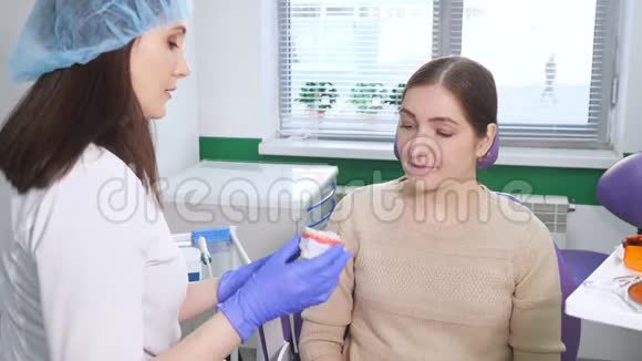 女牙医以牙模为例向年轻女性患者解释治疗方案牙齿护理概念视频的预览图