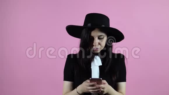 快乐的女人用粉色背景的智能手机视频的预览图