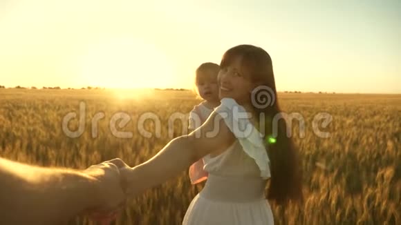 幸福的一家人牵着手跑过田野美丽的女孩带着女儿带着麦子走在田野上抱着她视频的预览图