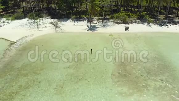 在菲律宾白沙滩和绿松石水中间的女人身上站着的无人机视频的预览图