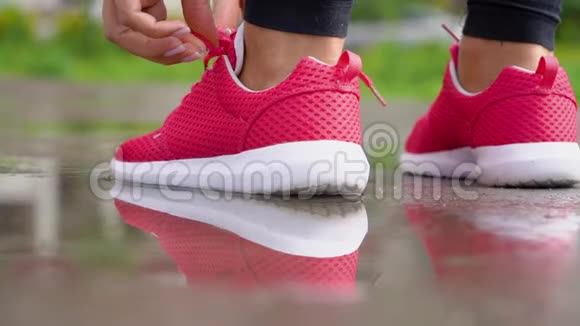 在雨天跑步女人系鞋带开始跑后景慢动作视频的预览图
