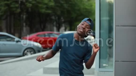 快乐的非洲男人在城市里跳舞用耳机听音乐视频的预览图