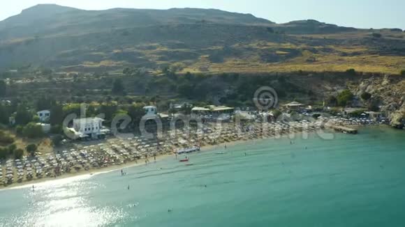 在海湾的海滩上飞行有沙滩海岸希腊日落人们游泳和日光浴罗德岛林德视频的预览图