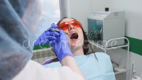 牙医正在给坐在椅子上的吓坏的年轻女人做麻醉刺伤视频的预览图