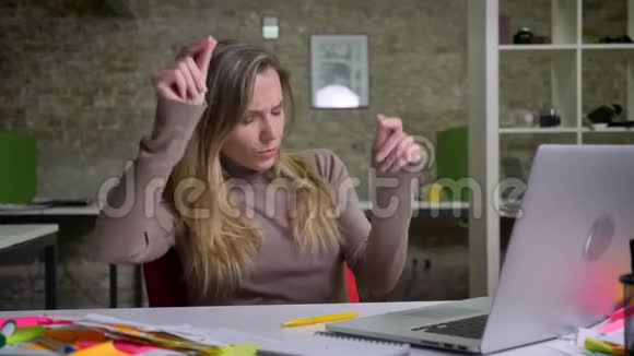漂亮的白种人女办公室工作人员坐在笔记本电脑前快乐跳舞的特写镜头视频的预览图