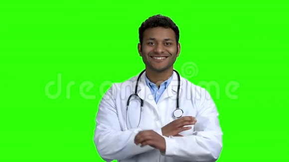 快乐的年轻医生双臂交叉在绿色的屏幕上视频的预览图