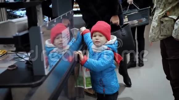 一个3岁的孩子站在超市收银员旁边看着货物视频的预览图
