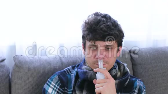 病人通过吸入器喷嘴吸入鼻子坐在沙发上特写面部正面视图使用雾化器视频的预览图